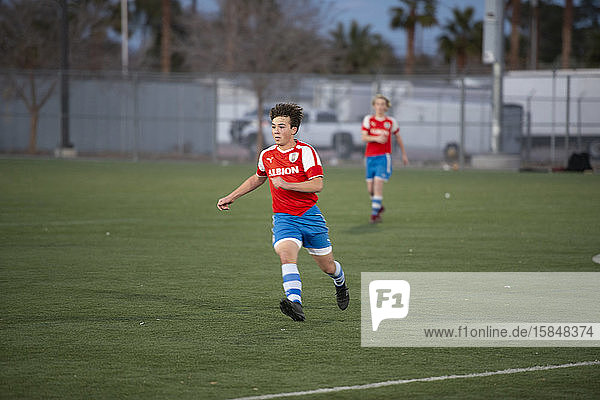 teen soccer player jogging on the field during a game
