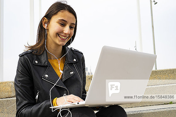 Junge Frau  die mit ihrem Laptop Musik hört.