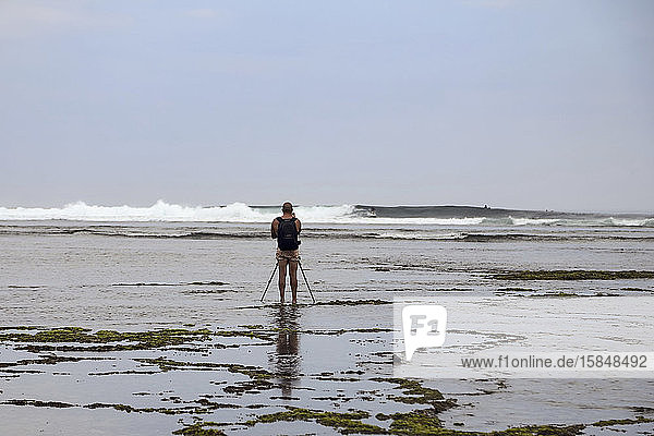 Fotograf mit Stativ beim Fotografieren eines Surfers