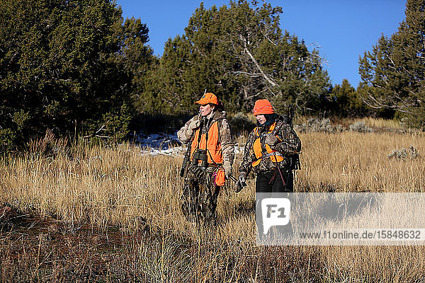 Zwei Jägerinnen wandern auf einer Wiese in Colorado