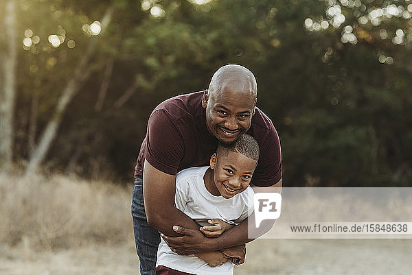 Nahaufnahme von glücklichem Vater und Sohn  die sich im Gegenlicht umarmen