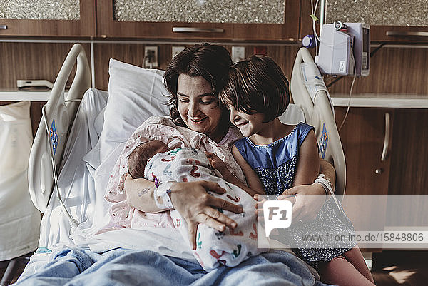 Mid view of mother holding newborn son meeting sister