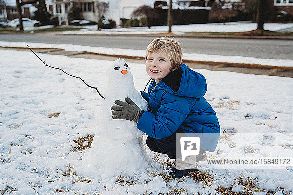 A little boy builds a snowman.