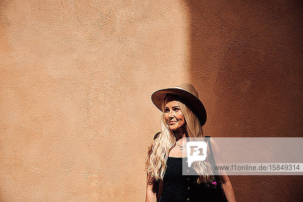 Stilvolle Frau lächelt an orangefarbener Wand
