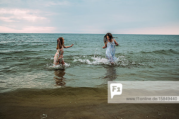 siblings splashing and playing in the water at lake michigan