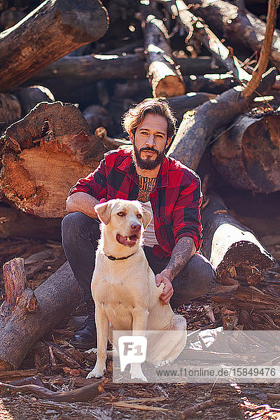 Porträt eines jungen tätowierten Mannes mit seinem Hund im Wald
