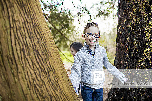Junge Brillenträger beim Spielen im Wald.