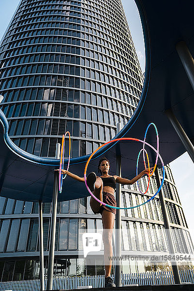 Aktive Frau führt Hula-Hoop-Tanz mit fünf Ringen im Stadtgebiet auf