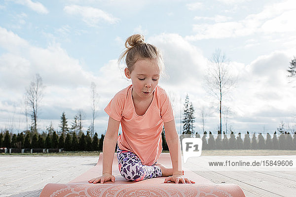 ein junges Mädchen  das zu Hause in ihrem Hinterhof Yoga-Stretching macht