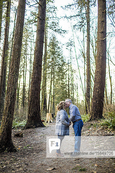 Älteres Paar küsst sich im Wald.