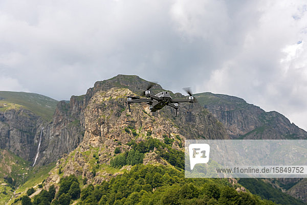 Drohne mit Kamera fliegt über Bergfelder.