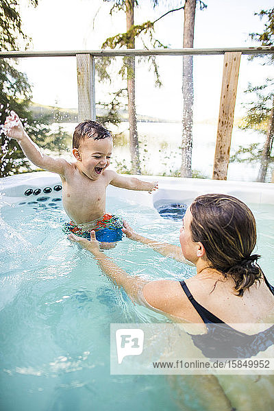 Young boy laughing and smiling with swimming ans splashing in pool.