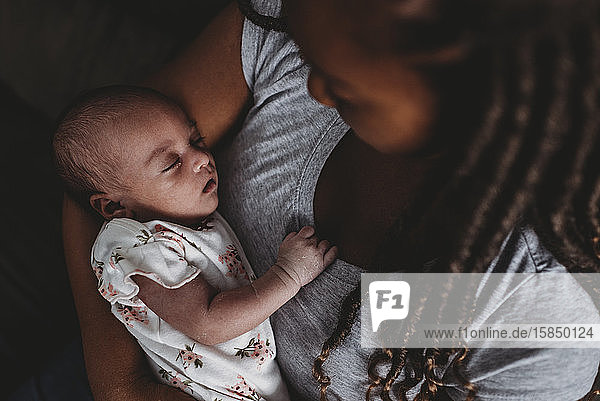 Kostbares multirassisches Kleinkind schläft friedlich in der Umarmung der Mutterâ€™s