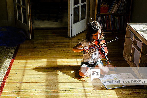 Ein kleines Kind sitzt allein in einem sonnenbeschienenen Geigenspielplatz