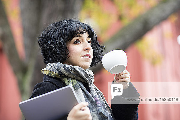 young woman with a coffee cup outside