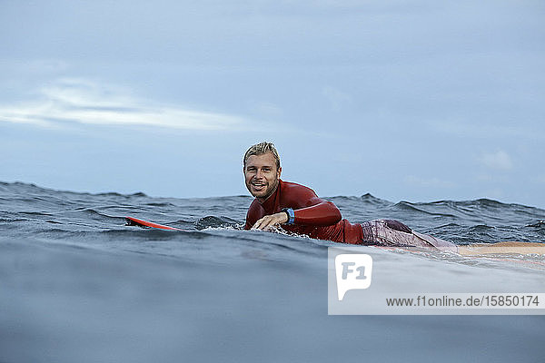 Auf einem Surfbrett auf dem Meer liegender Mann