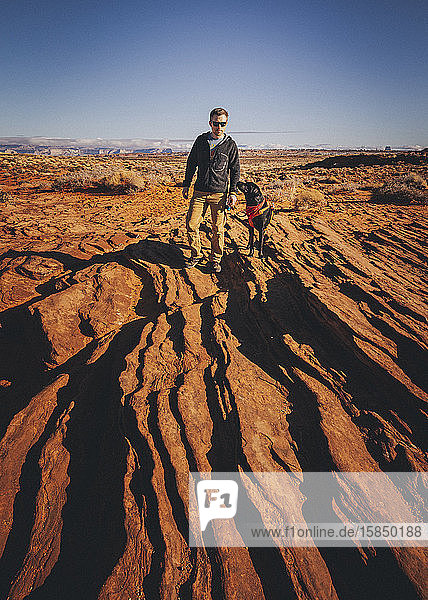 A man with a dog is standing near Horseshoe Bend  Arizona