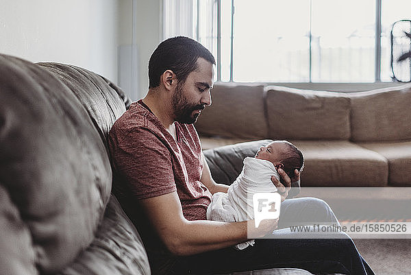 Mid-30â€™s dad with beard holding swaddled infant