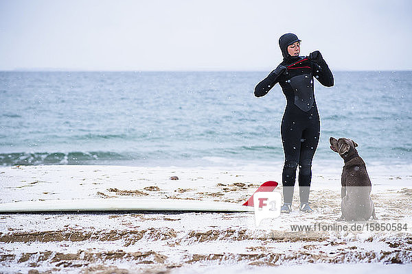 Young woman and dog going winter surfing in snow