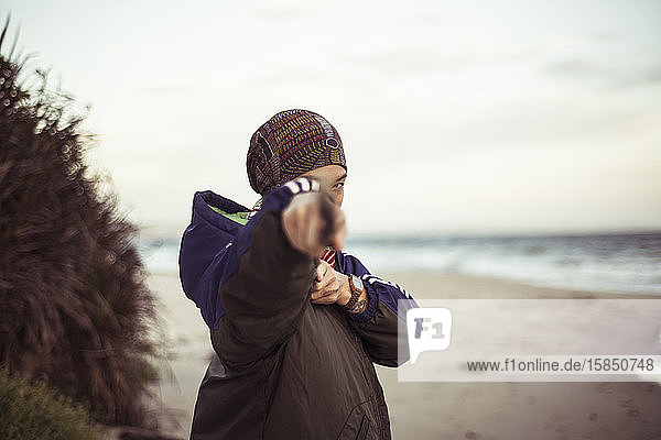 androgyner asiatischer Point-Ninja-Stock vor der Kamera am abgelegenen Strand in der Abenddämmerung