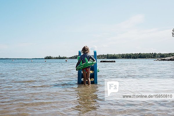 Mädchen mit Schlauchboot beim Spielen auf einer Rutsche im Meer im Sommer