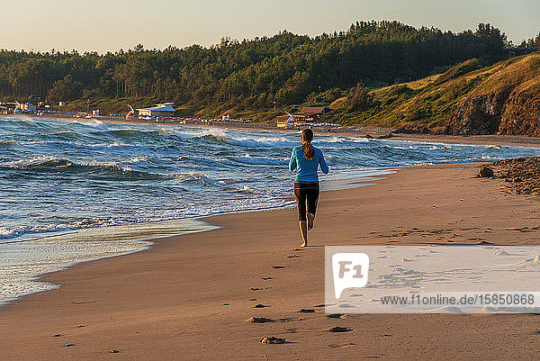 Junges sportliches Mädchen läuft am Strand