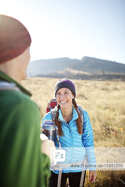 Female backpacker with water bottle laughing with male backpacker
