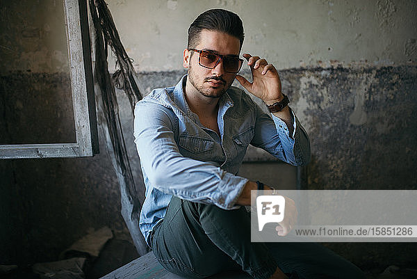 Portrait of a handsome young man with sunglasses in old house.