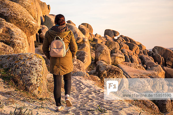 Frau  die bei Sonnenuntergang an der Küste spazieren geht. Ribeira  Spanien