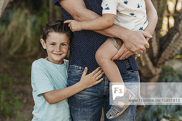 Mid view of elementary age boy hugging father and brother and smiling