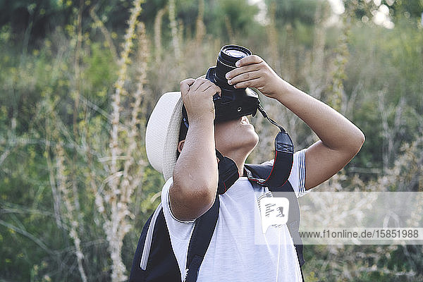 Kid photographer with white hat taking photos with his camera
