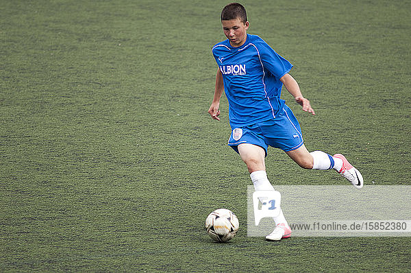 Teen soccer player dribbling the ball during a game
