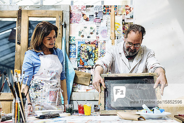 Inspired mature artisans working in screen printing studio