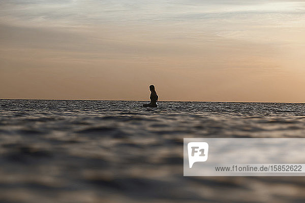 Female surfer in ocean at sunset