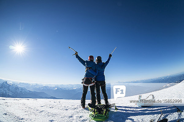 Zwei glückliche Bergsteigerinnen erheben zum Sieg ihre Eispickel