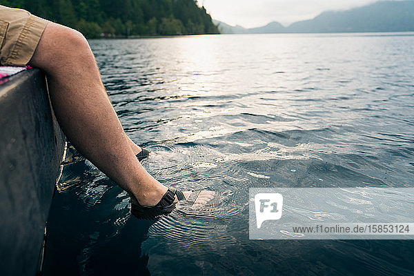 Männerfüsse in Sandalen in den See getaucht