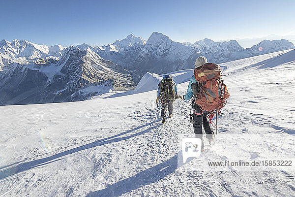 Woman mountaineer & cimbing Sirdar descend a glacier  Everest on left