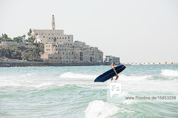 Surft als weibliche Surferin in Israel in die Wellen