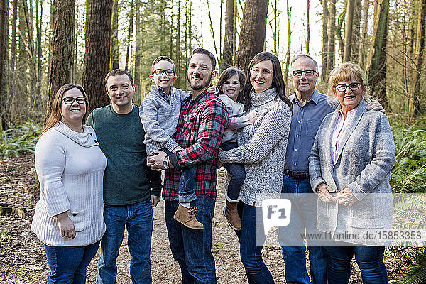 Nahaufnahme eines Porträts einer glücklichen achtköpfigen Familie im Wald.