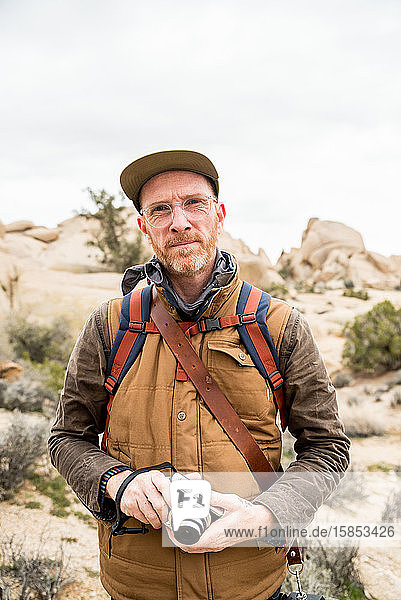 Fokussierter reifer Mann mit Kamera und Rucksack in der Wüste