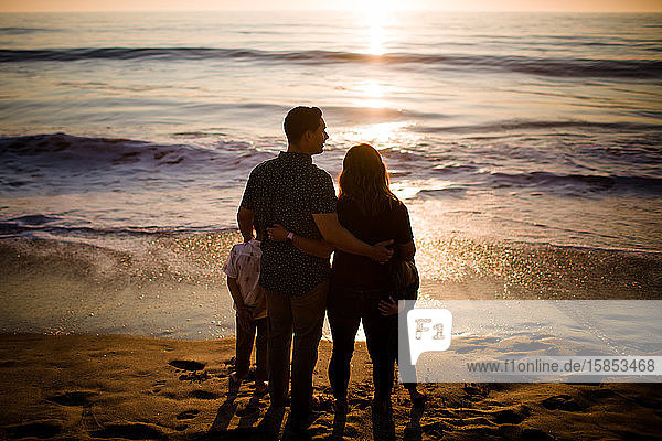 Family of Four Standing on Beach  Looking at Ocean at Sunset
