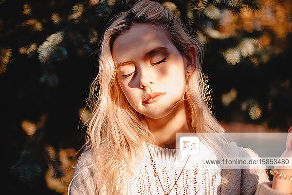 Portrait of young woman with eeditorial closed standing in front of sunlight