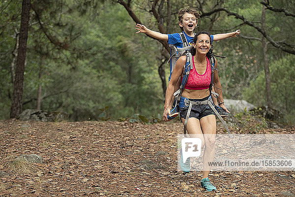 Mom running with his toddler in a backpack on a forrest at Huasca de Ocampo  Mexico
