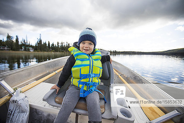 Young boy sitting in aluminum boat during fishing trip.