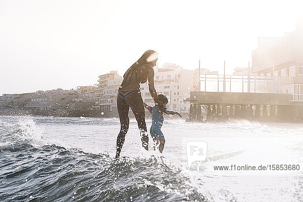 Gesamtansicht von Mutter und Sohn beim Surfen auf einer kleinen Welle auf See