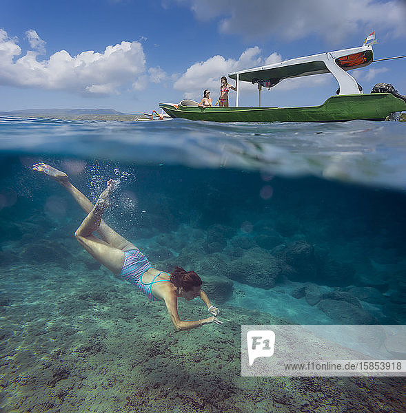 Young woman snorkeling near the boat in ocean  underwater view