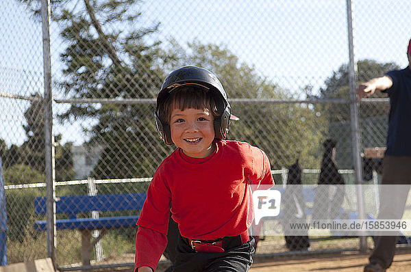 Junge mit Baseballhelm und großem Lächeln auf dem TBall-Feld