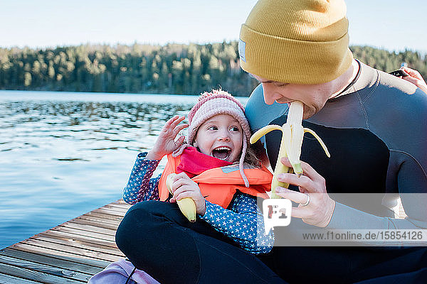 Vater und Tochter essen im Winter im Urlaub Obst am Strand