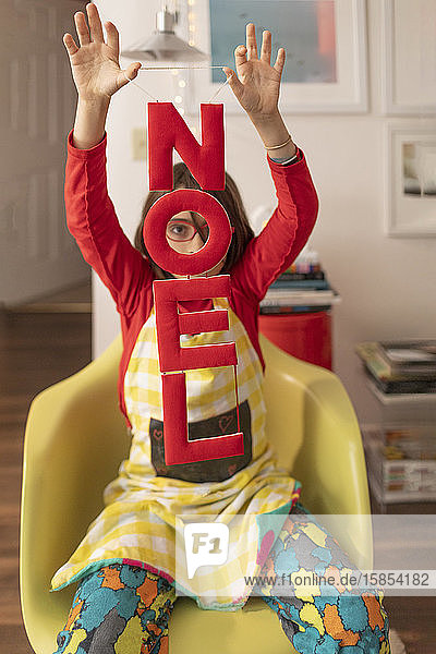 Child holding Noel Banner at home