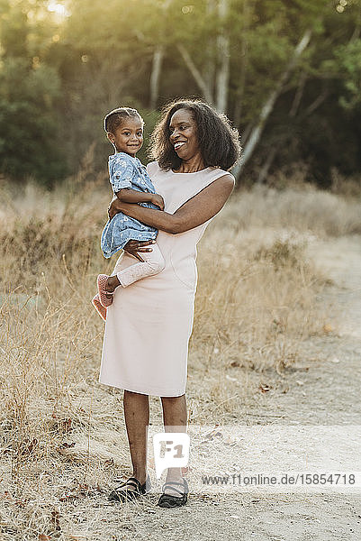 Portrait of happy grandmother holding young granddaughter on-loc